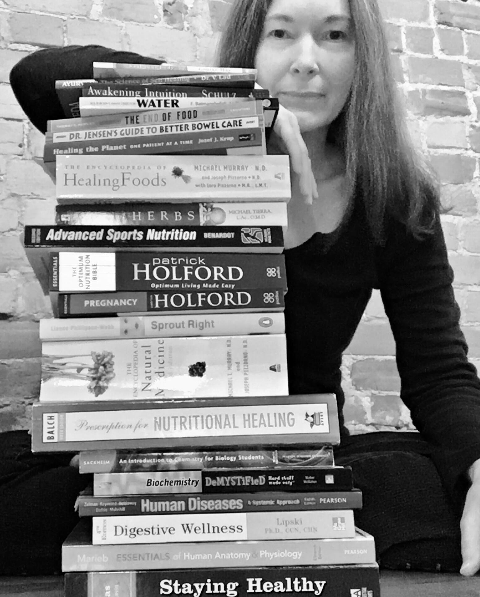 A photo of Michelle with a pile of her IHN textbooks.